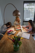 Homeschooling, during the lockdown in January 2021, mother helps her two daughters, at home,