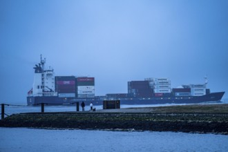 Thick fog in winter, hangs over the mouth of the Elbe into the North Sea, container ship enters the