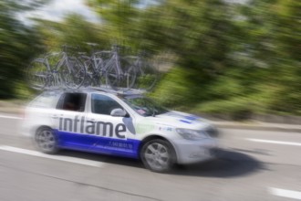 Support vehicle at a cycle race with bicycles on the roof, fast movement emphasised by blurring,