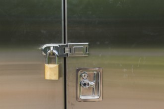 Close-up of stainless steel door on a utility cabinet locked with a brass padlock, Quebec, Canada,