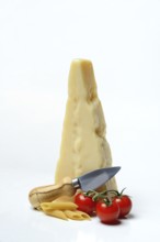 A piece of Parmesan cheese with cheese knife, tomatoes and pasta, Italy, Europe