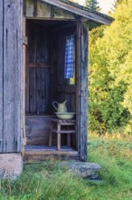 Old wooden outhouse with a sink and a jug at an old cottage in the countryside, Sweden, Europe