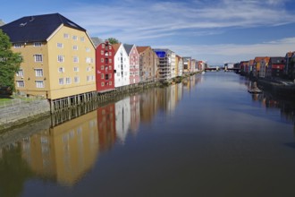 Riverbank with modern and colourful wooden buildings reflecting in the calm water, Nidarelva,