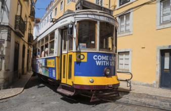 A yellow-blue tram winds its way through a cobbled street surrounded by historic buildings, Tram,