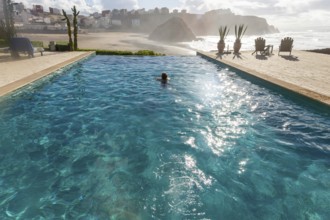 Woman swimming infinity pool by Atlantic Ocean, Hotel auberge Dar Najmat, Mirleft, Morocco, north