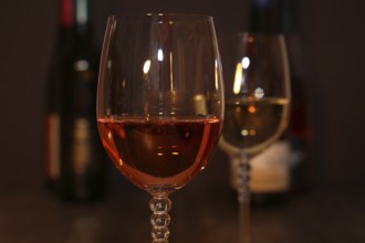 Close-up of two glasses of wine with wine bottles in the background