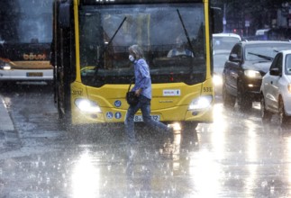 People run across Potsdamer Strasse in heavy rain. After weeks of heat, the first heavy rain