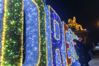 Augustusmarkt in Dresden. a woman looks through the illuminated sign DRESDEN, Dresden, Saxony,