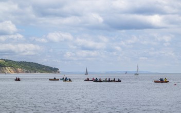 People in a canoe on Seaton Bay with the Haven Cliffs Naturist Beach in the background, Jurassic