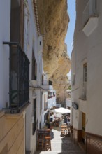 Narrow alley in Setenil de las Bodegas under rocks, summer scenario, cave dwellings, Setenil de las