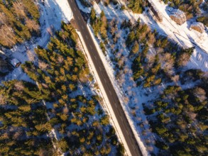 Straight road divides snowy forest from a bird's eye view, Seewald, Black Forest, Germany, Europe