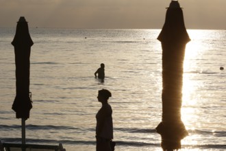 First swimmers at sunrise on the beach of Diano Marina, Italy, 14/08/2024, Diano Marina, Liguria,