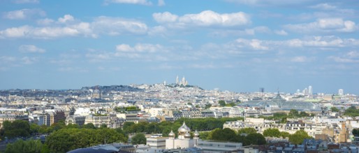 View over the rooftops of Paris on a sunny day in summer with few clouds, white city with some