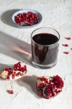 Glass of pomegranate juice on a white concrete background. Hard light, contrast. Side view, close