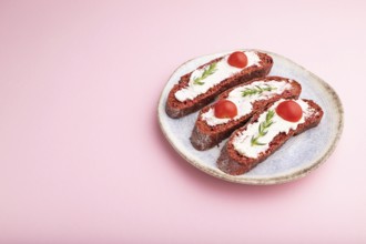 Red beet bread sandwiches with cream cheese and tomatoes on pastel pink background. Side view, copy