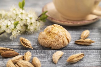 Almond cookies and a cup of coffee on a gray wooden background and green linen textile. Side view,