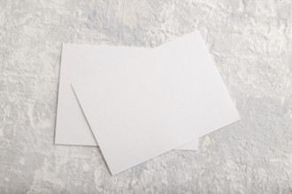 White paper business card, mockup on gray concrete background. Blank, flat lay, top view, still