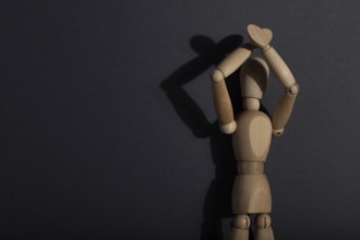 Wooden mannequin stands with raised hands on gray background. protest, attention concept. copy