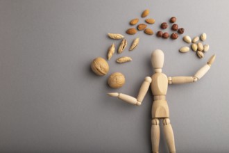 Wooden mannequin juggling nuts on gray pastel background. close up, isolated, delivery concept,