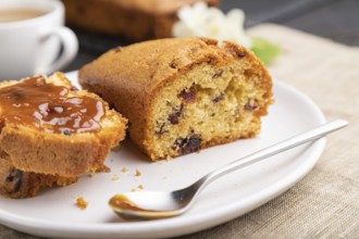 Homemade cake with raisins, almonds, soft caramel and a cup of coffee on a black concrete