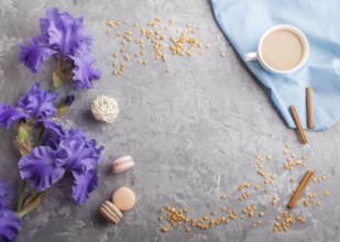 Purple iris flowers and a cup of coffee on a gray concrete background. Morninig, spring, fashion