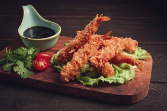 Fried shrimp, peeled in tempura, soy sauce, close-up, on a wooden board