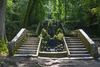 Steintreppe im Wald mit moosbedeckten Geländern und einem kleinen Wasserfall in der Mitte, Quelle