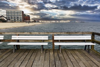 Empty benches on the pier with a view of the beach, houses and ferry port, autumn weather, Wyk auf