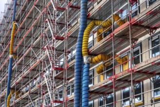 Large construction site, scaffolded shell of an office building complex, air hoses for building