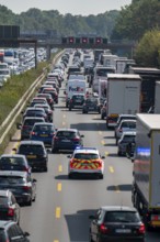 Emergency ambulance with flashing blue lights and siren working its way through a traffic jam on