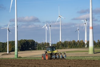 Farmer working in the fields, with a tractor, wind farm above the village of Lichtenau,