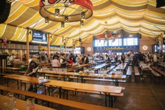 Tidy marquee with empty tables, few visitors are still there, Canstatter Wasen, Stuttgart, Germany,