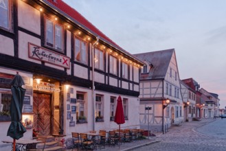 A festively illuminated restaurant in the evening and half-timbered houses in the cobbled