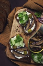 Sandwiches, black bread with sprats, cream cheese, cucumbers, on a cutting board, top view,