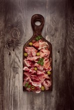 Assortment, sliced meat appetizer, prosciutto, salami and ham, with olives, on a wooden board,