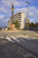 Flat hotel, granite column with metal sculpture of a cog, roundabout between the streets