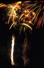 New Year's Eve fireworks, vivid fireworks in the night sky with golden, yellow and red streaks of