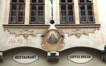 Old historic façade with image of the Virgin Mary and signs for restaurant and coffee break in the