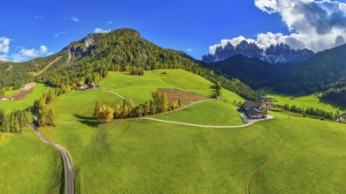 Farm and alpine meadows, in the background the peaks of the Geisler group, panoramic shot, drone