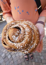 Women's hands with a traditional cinnamon bun, Haga neighbourhood, Gothenburg, Västra Götalands län