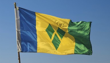 The flag of the Grenadines flutters in the wind, isolated against a blue sky