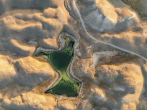 Green lakes between golden hills with gravel road, top down shot, aerial view, Trans Alay