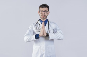 Doctor praying with hands together on isolated background. Young doctor praying with hands together