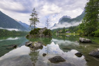 Hintersee with rocks and trees in the foreground, surrounded by mountains, cloudy sky, Ramsau,