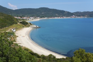 View of a quiet coastal landscape with beach and azure blue sea, surrounded by hills and small