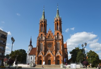 Red brick church with two towers and outbuildings under a cloudy sky, Church of the Blessed Virgin