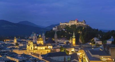 Night view of Salzburg with illuminated historical buildings and the Hohensalzburg Fortress in the