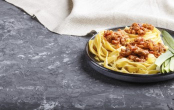 Tagliatelle bolognese pasta with minced meat on a black concrete background. side view, close up,