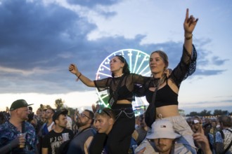 Festival visitors celebrate on shoulders during Ski Aggu's performance in front of the Ferris wheel