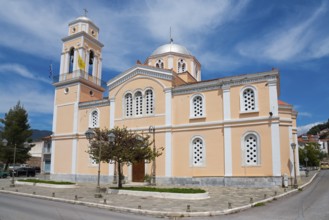 Neoclassical church with pink façade on a street corner, Greek flag flying, Church of Agios